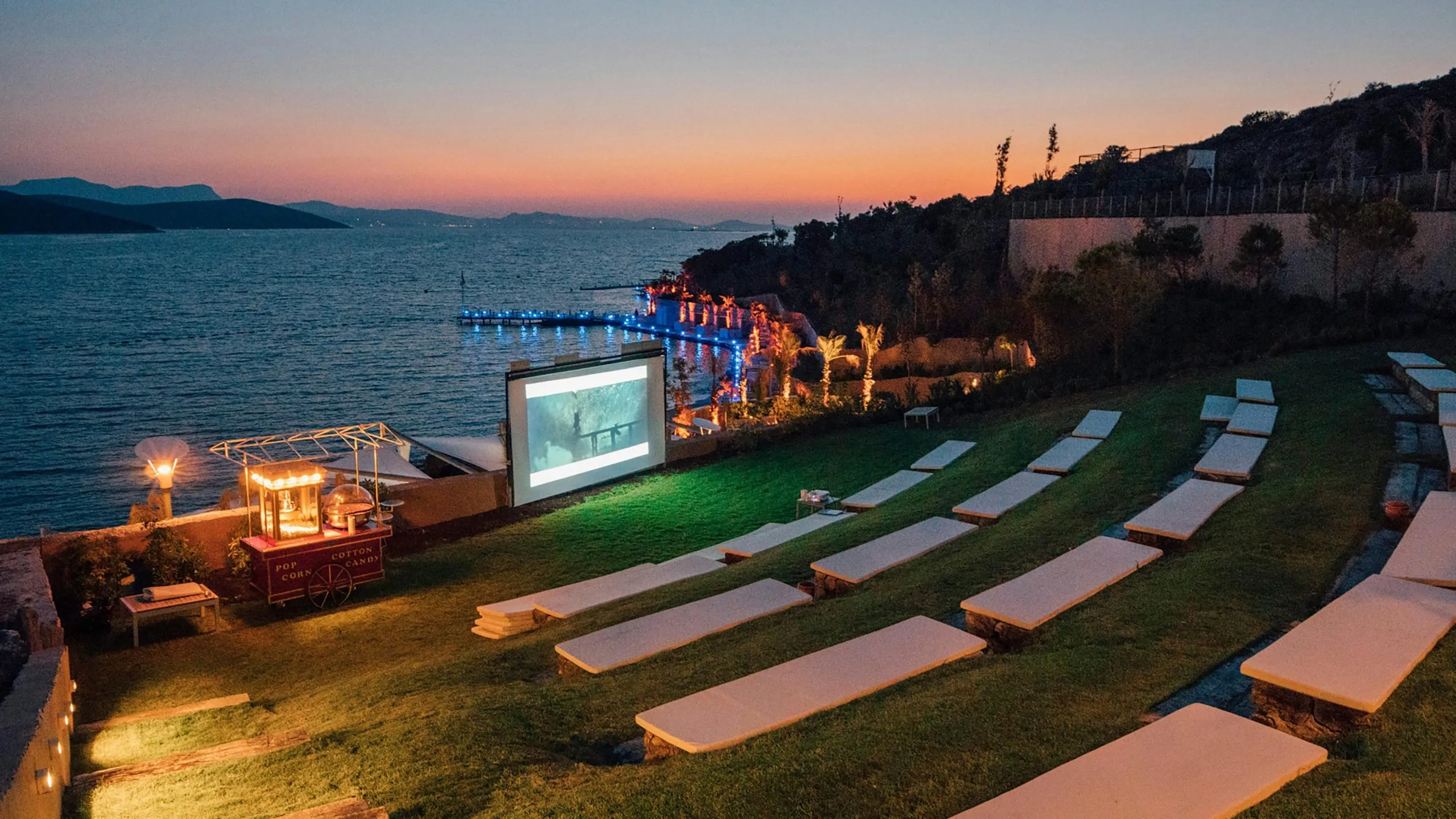 Outdoor cinema experience in Dubai with large screen showing movie and guests watching on grass under stars