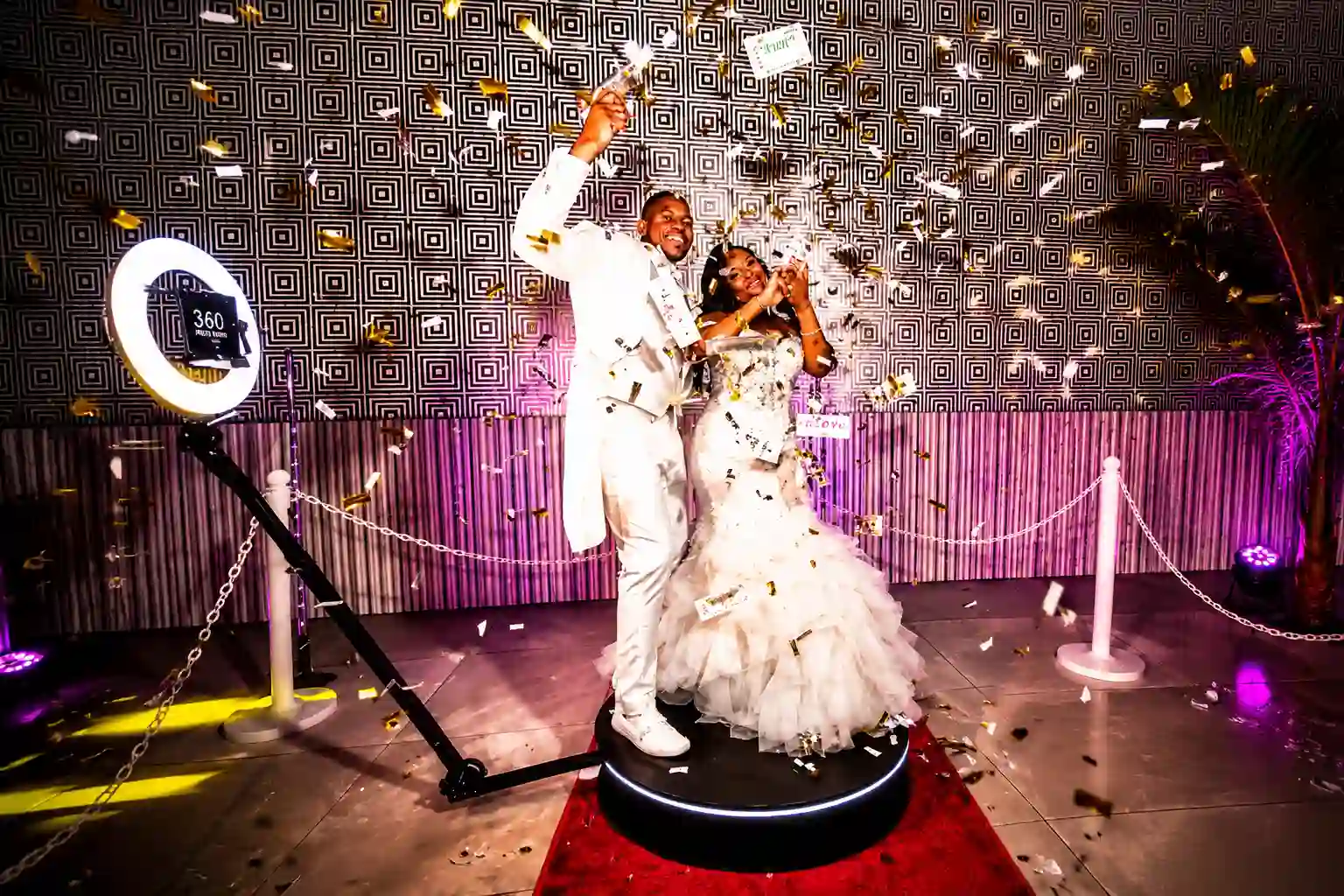 Bride and groom celebrating on a 360 video booth platform surrounded by gold confetti during their wedding reception, creating a fun and memorable interactive entertainment experience.