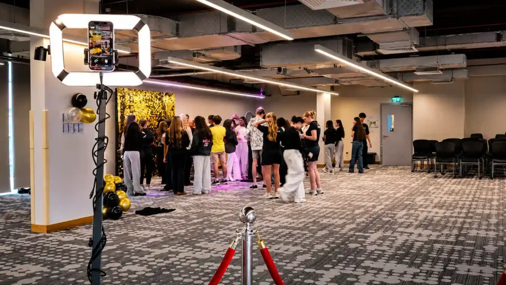 Students gather around a Box Entertainment 360 photo booth with a gold sequin backdrop at a school celebration in Dubai, creating fun memories in a bright, modern event space.