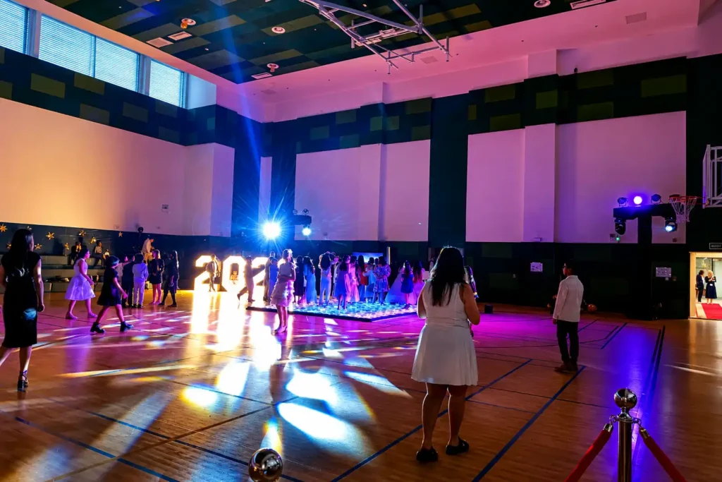 Students dancing on an LED dance floor with professional DJ lighting and illuminated graduation numbers at a school prom in Dubai, produced by Box Entertainment.