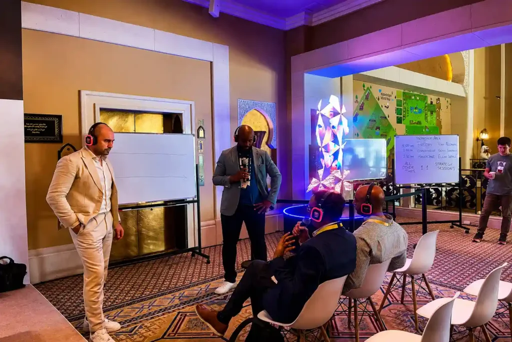Corporate workshop using silent disco headphones, with a presenter speaking to attendees in a conference venue. Participants wear wireless headsets for clear audio during an interactive business seminar and training session in Dubai.