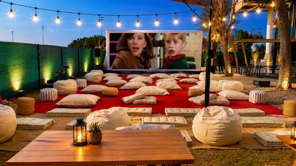 Luxury outdoor cinema setup in Dubai featuring a large LED movie screen, comfortable bean bags, floor cushions, ambient festoon lighting, and relaxed lounge seating for a private movie night or corporate event.