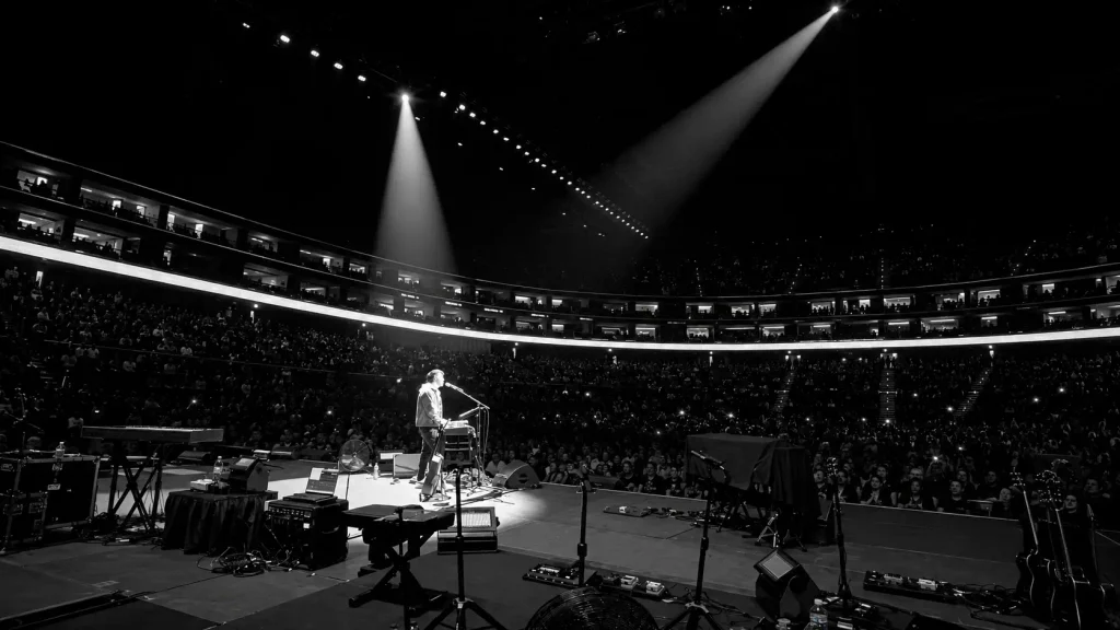 Greg Pearson performing live under spotlights to a large audience at an indoor arena in Dubai, UAE.