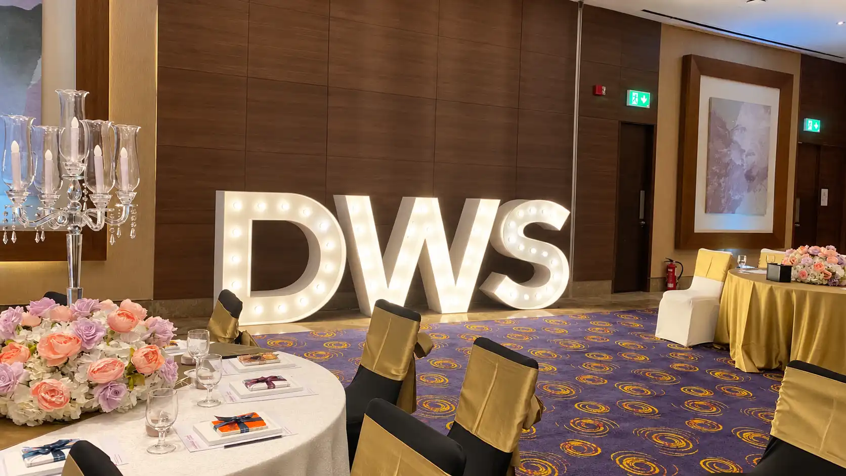 Illuminated DWS letters by Box Entertainment beside floral table arrangements at the Dubai Wedding Summit & Awards in Mövenpick JBR’s Melrose Ballroom.